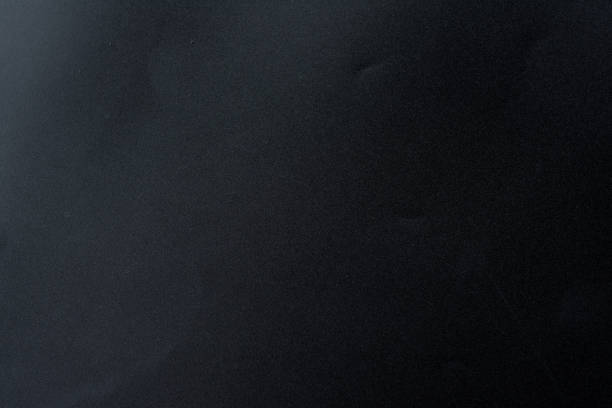 istock Black rough textured background lit with dim light at the angle. 1130732433