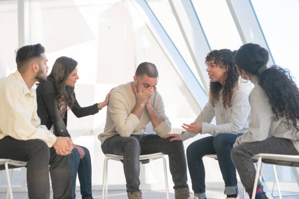 istock Young adults consoling a friend in group therapy 1130735355