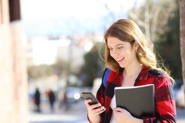 istock Happy student uses smart phone in the street 1130738105