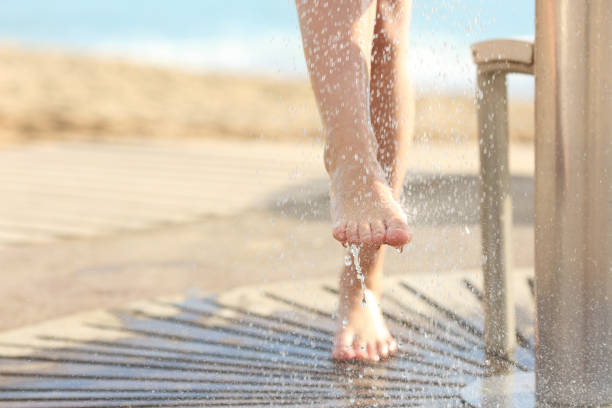 женщина очистки ног в душе после пляжного дня - human leg women shower water стоковые фото и изображения