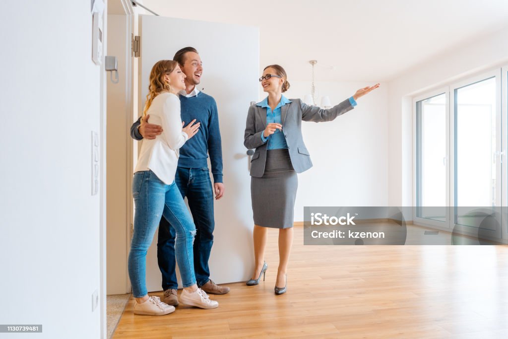 Real Estate Agent showing house to a young couple Real Estate Agent showing house to a young couple wanting to rent it Real Estate Agent Stock Photo