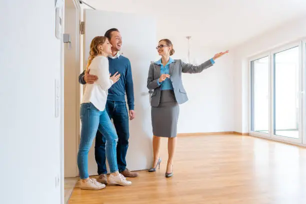Photo of Real Estate Agent showing house to a young couple