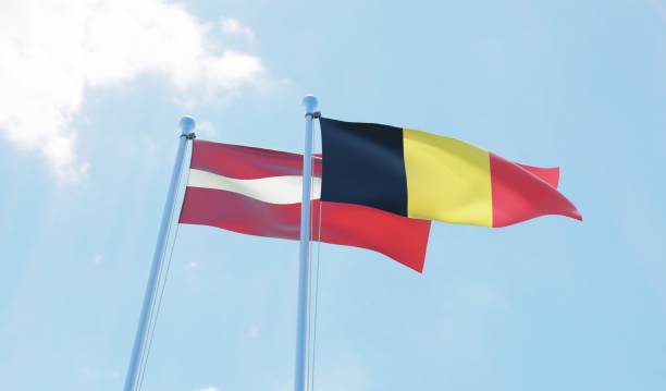 istock Latvia and Belgium, two flags waving against blue sky 1130739726