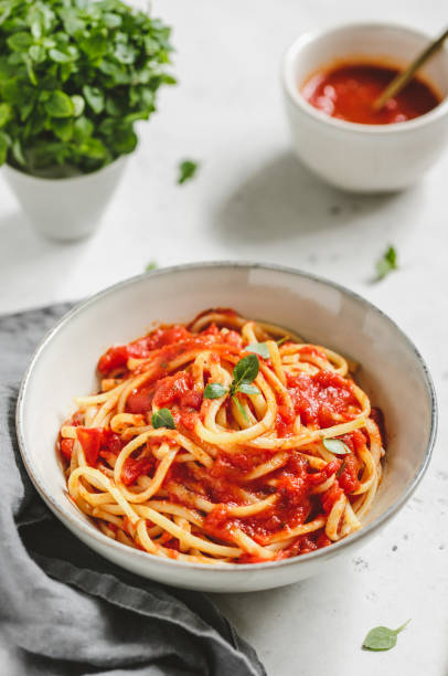 istock Traditional pasta with tomato and Greek basil sauce in a ceramic bowl on a white table. 1130744596