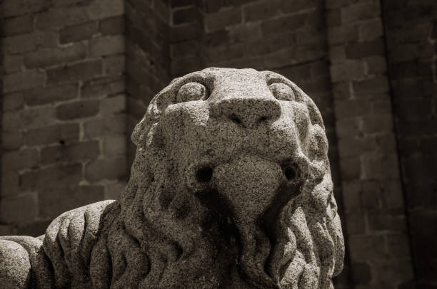 Close-up of elegant sculpture of a lion muzzle carved on stone at Avila. It has the longest and imposing wall completely encircling this well-kept gothic town in Spain. Black and white photo.