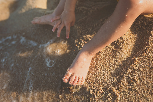 Close-up of a baby foot at the beach playing in the sand