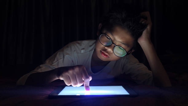 istock Asian boy pressing digital tablet at night with serious face. 1130753711