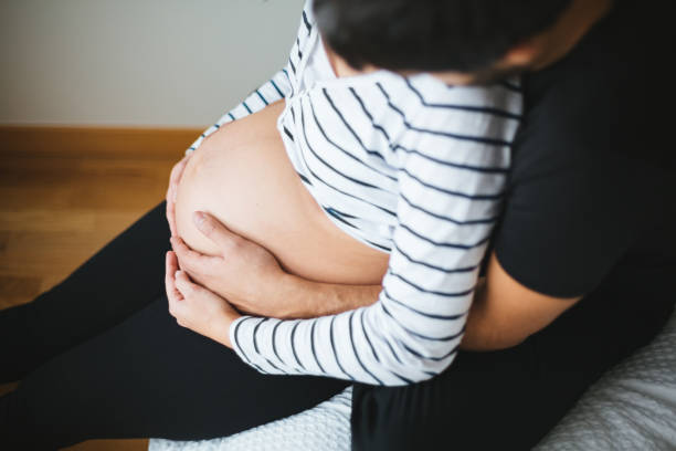 istock Pregnant couple hugging and touching womans belly 1130754780