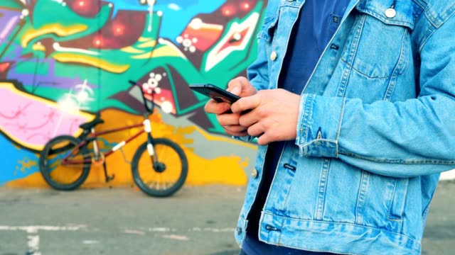 Teenager typing on a phone on a bicycle background, close up.