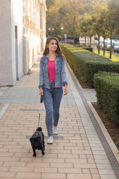 istock Young woman and her dog walking on sidewalk 1130757145