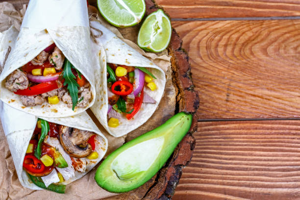 Tasty homemade burrito with vegetables and beef on wooden rustic textures. Mexican restaurant fast food. place for text. top view Tasty homemade burrito with vegetables and beef on wooden rustic textures. Mexican restaurant fast food. place for text. top view. mex mexican restaurant tex stock pictures, royalty-free photos & images
