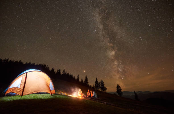 istock Friends resting beside camp, campfire under night starry sky 1130760240