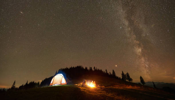 istock Friends resting beside camp, campfire under night starry sky 1130760254