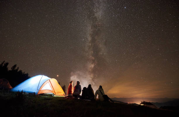 istock Friends resting beside camp, campfire under night starry sky 1130760255