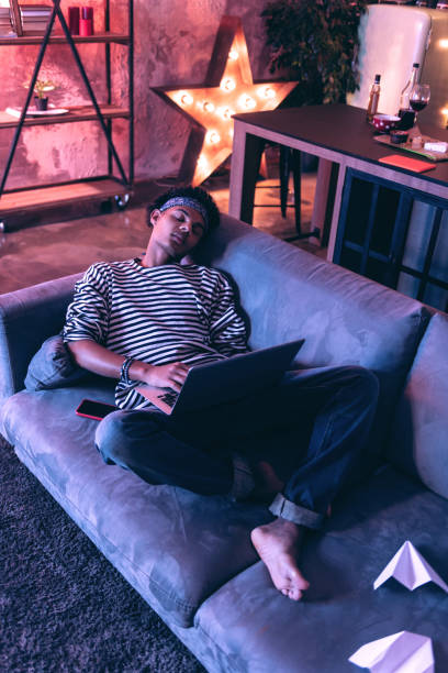 istock Adult boy falling asleep on a couch while doing boring homework. 1130760557