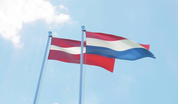 istock Latvia and Netherlands, two flags waving against blue sky 1130760858