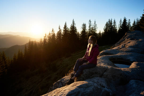 istock Woman hiker sitting on boulder in the mountains at sunset 1130761790