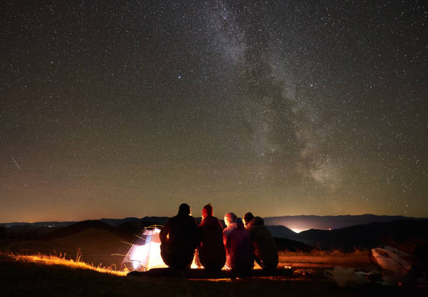 istock Friends resting beside camp, campfire under night starry sky 1130761792