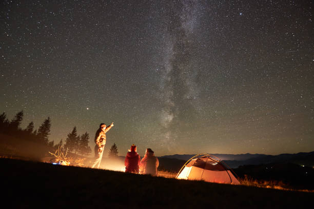 istock Friends resting beside camp, campfire under night starry sky 1130761794