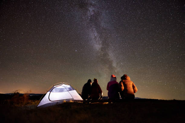 istock Friends resting beside camp, campfire under night starry sky 1130761799