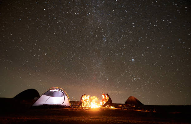 istock Friends resting beside camp, campfire under night starry sky 1130761800