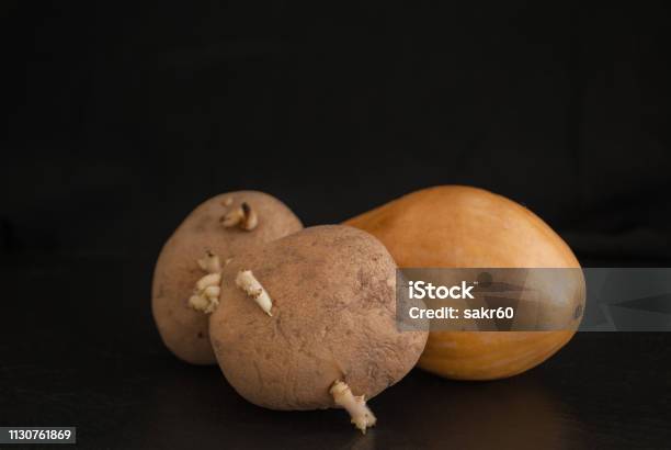 Potato With Sprouts And Pumpkin On A Black Background Stock Photo - Download Image Now