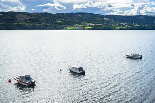 Three boats surrounded by the beautiful landscape of Mjosa lake during summer, Hedmark, Norway