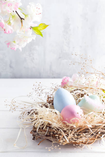 istock Beautiful flower with colorful eggs in nest on light background. Spring and Easter holiday concept with copy space. 1130763180