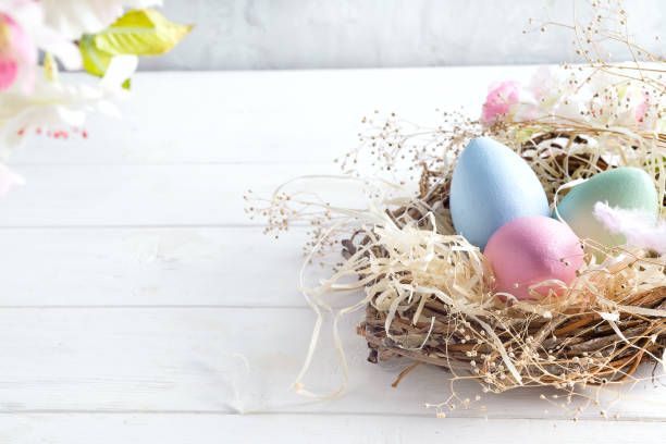 istock Beautiful flower with colorful eggs in nest on light background. Spring and Easter holiday concept with copy space. 1130763716