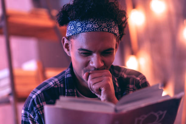 istock Close up of a young man giggling about something that he finding in the book. 1130763817