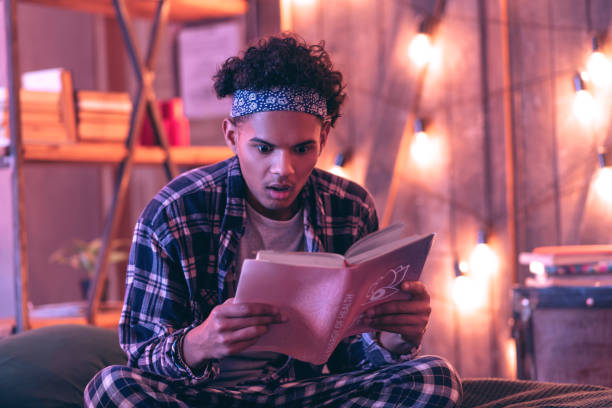 istock Confused boy revealing the secrets that the book hid from everyone. 1130763895