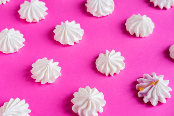 istock Pattern with meringues on a pink background. Multicolored meringues on a pink background. Basis for confectionery banner, cafe, sweet shop. Meringue banner 1130765675