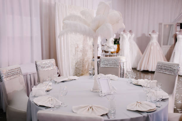 istock White dinner table decorated with flowers, feathers. Metallic silver wedding decor at luxury style. 1130768849