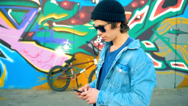 Person texting on his phone in a skatepark. Young stylish Caucasian male teenager.