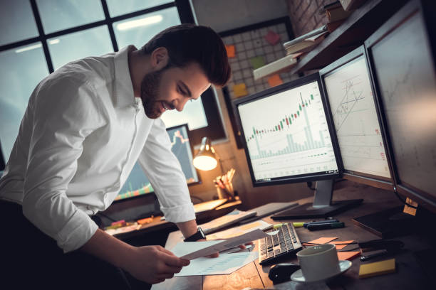 istock Young male trader at office work concept standing looking at documents cheerful 1130771080