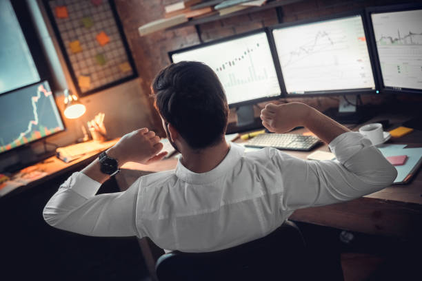 istock Rear view at stock trader broker stretching hands at workplace 1130771107