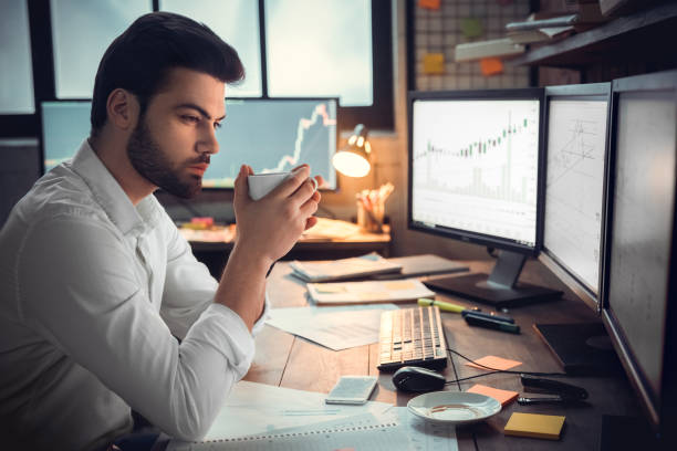 istock Thoughtful serious trader broker drinking coffee analyzing stock market graphs 1130771151