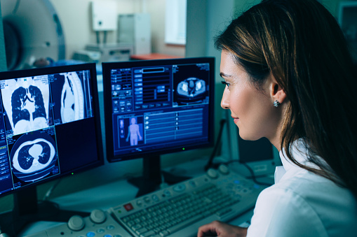 Radiólogo leyendo una tomografía computarizada. Médico femenino que ejecuta tomografía computarizada desde la sala de control en el hospital photo