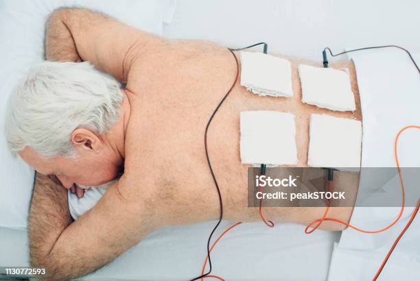 Physiotherapeutic Treatment Senior Patient Having Ultrasound And Electrotherapy Treatment On His Back Stock Photo - Download Image Now