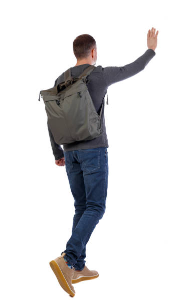 istock Back view of a walking man with a bag pointing his hand up. 1130781328