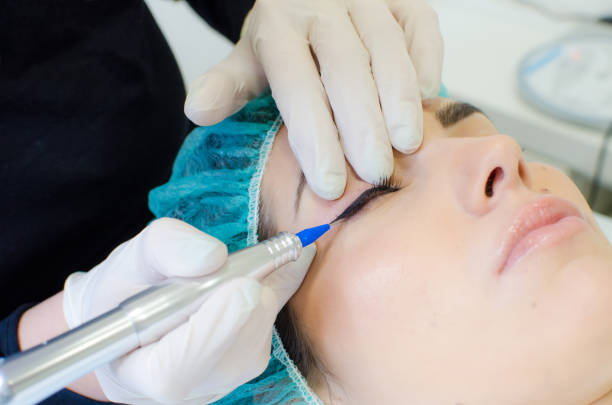 istock Permanent make-up tattoo. Cosmetologist applying permanent make up eyeliner 1130782553
