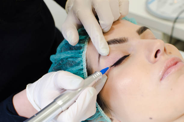 istock Permanent make-up tattoo. Cosmetologist applying permanent make up eyeliner 1130783095