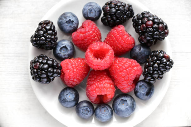 istock Berries: blackberries, blueberries, rasberries on a white wood background 1130783538