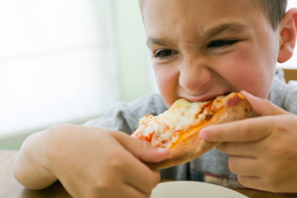istock Boy eating cheese pizza in the house 1130785237