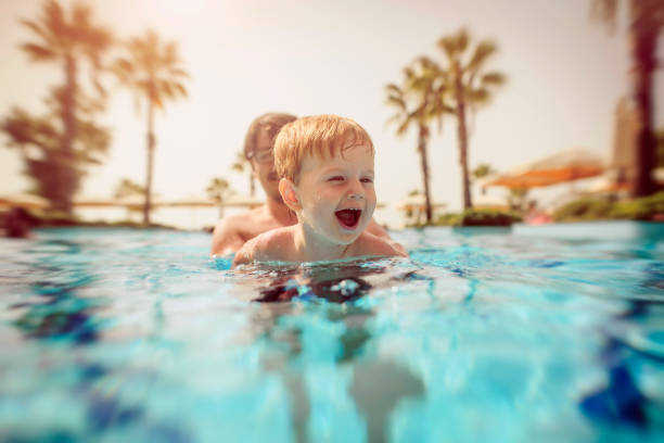 istock Happy little boy with his father in swimming pool 1130785538
