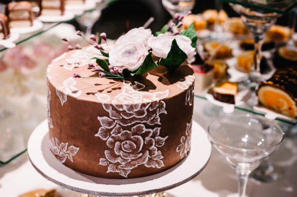 istock White and brown wedding cake with pink flowers and greens on a festive table and blur background. 1130791237