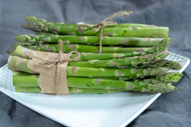 istock Fresh raw green asparagus vegetable on white board, close up 1130798287