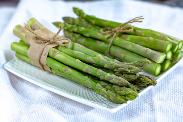 istock Fresh raw green asparagus vegetable on white board, close up 1130798307