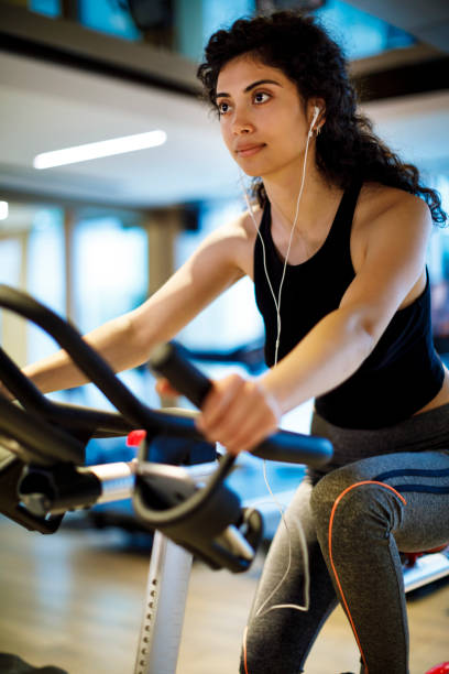 istock Young woman practicing on exercise bike at the gym 1130800553