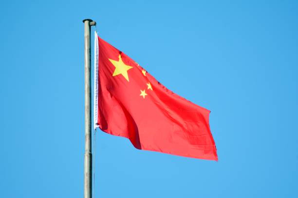 istock Chinese flag with flag pole waving in the wind over blue sky background 1130803056